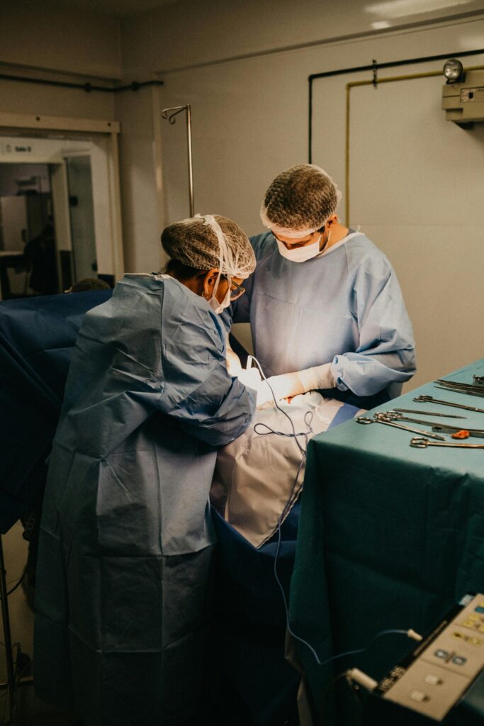 Two surgeons in an operating room conducting surgery under bright lights.